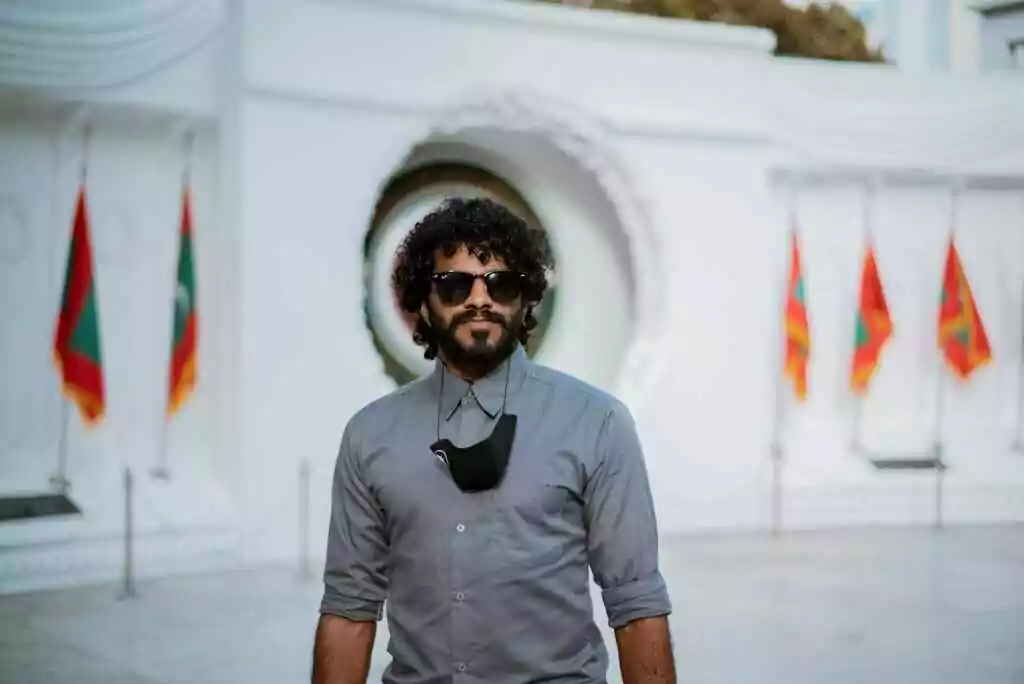 Your World Awaits: 15+ Visa-on-Arrival Countries for UAE 18 A man with curly hair and sunglasses poses in front of a monument with Maldives flags.