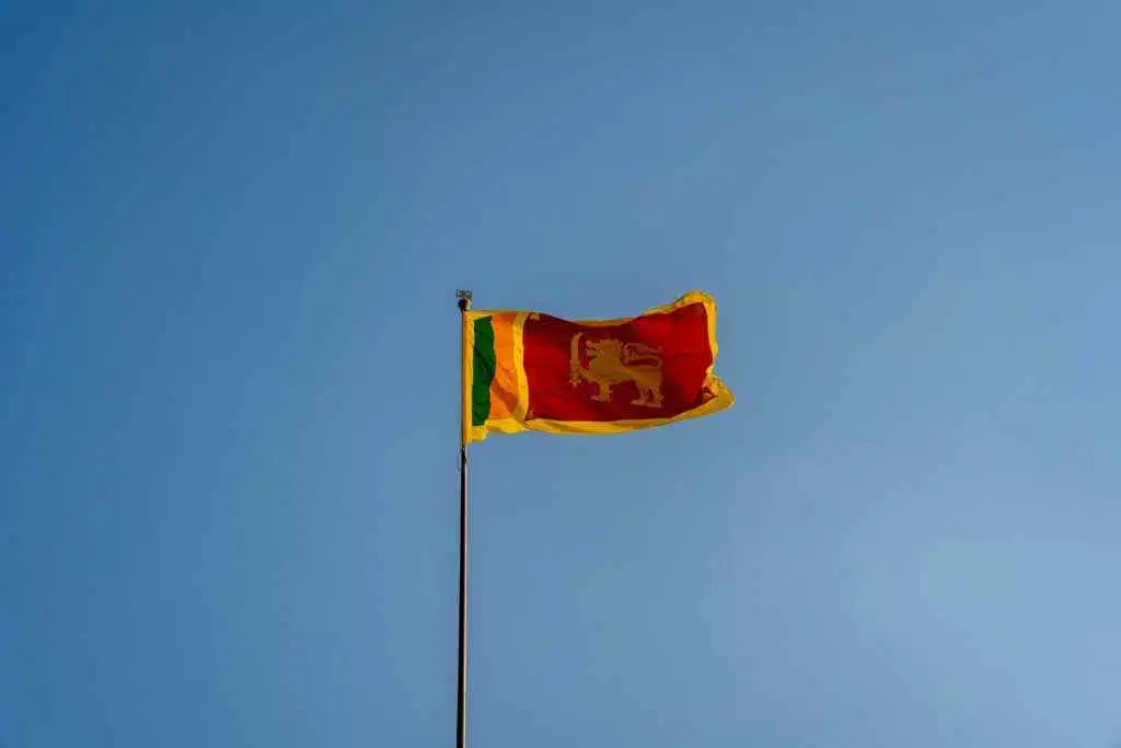 Your World Awaits: 15+ Visa-on-Arrival Countries for UAE 27 Sri Lanka national flag waving on a flagpole under a clear blue sky. Captured in mid-air with vibrant colors.