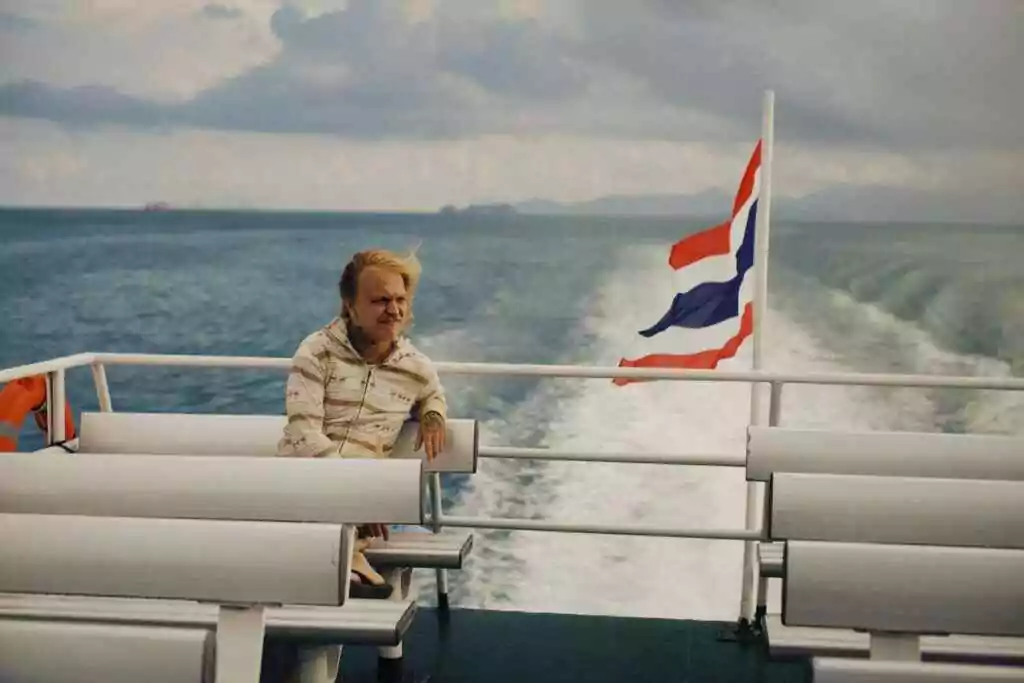 Your World Awaits: 15+ Visa-on-Arrival Countries for UAE 32 A man sitting on a ferry with the Thailand flag waving in the wind over the sea.