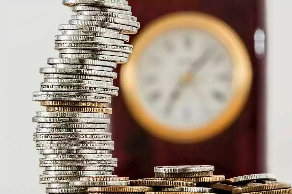 FAB Ratibi Card Balance: 3 Hidden Methods 14 A close-up image of stacked coins with a blurred clock, symbolizing time and money relationship.