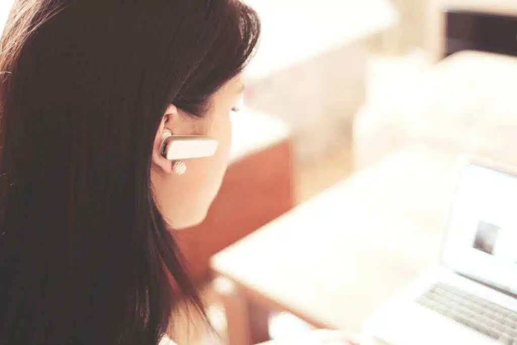 NBAD Balance Inquiry UAE – 7 No-Fee Methods in 2025 24 A businesswoman using a Bluetooth headset while working on her laptop in a modern office.