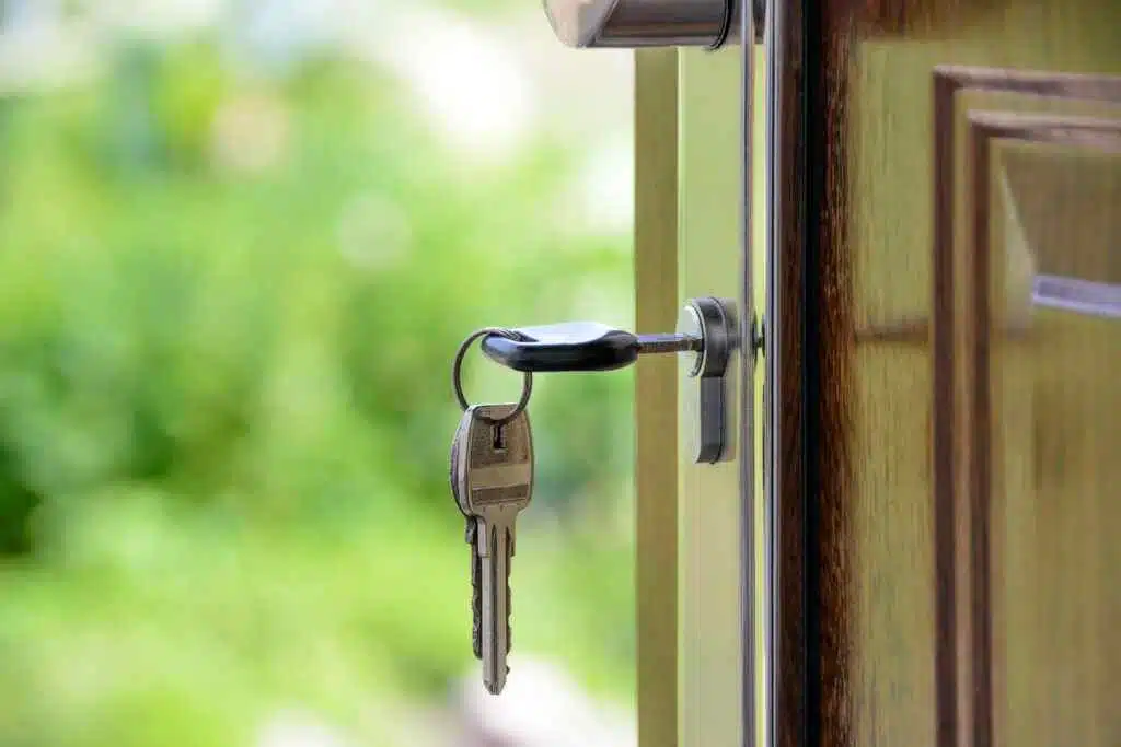 Mortgage Calculations in UAE for Different Scenarios Key inserted in door lock against a blurred green background, symbolizing security and real estate.