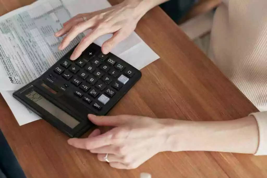 VAT Calculation in UAE for Different Scenarios Close-up of a woman using a calculator and reviewing bills at home.