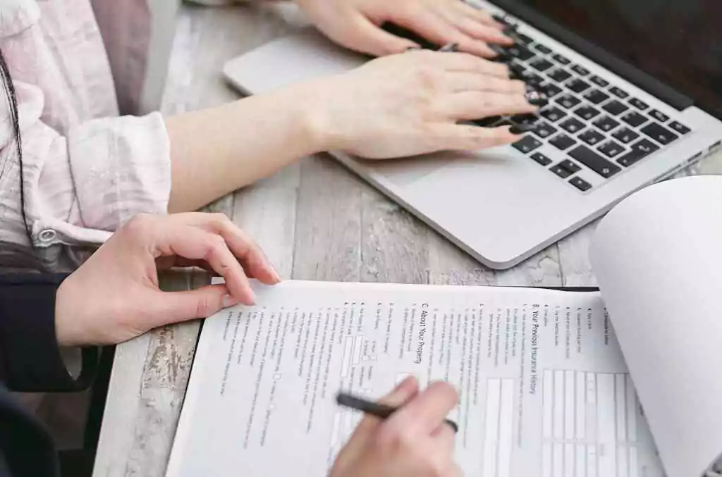 Instant Etisalat Loan Code: Secret USSD Revealed 2025 8 Close-up of hands typing on a laptop and reviewing business documents, focused on finance and legal tasks.