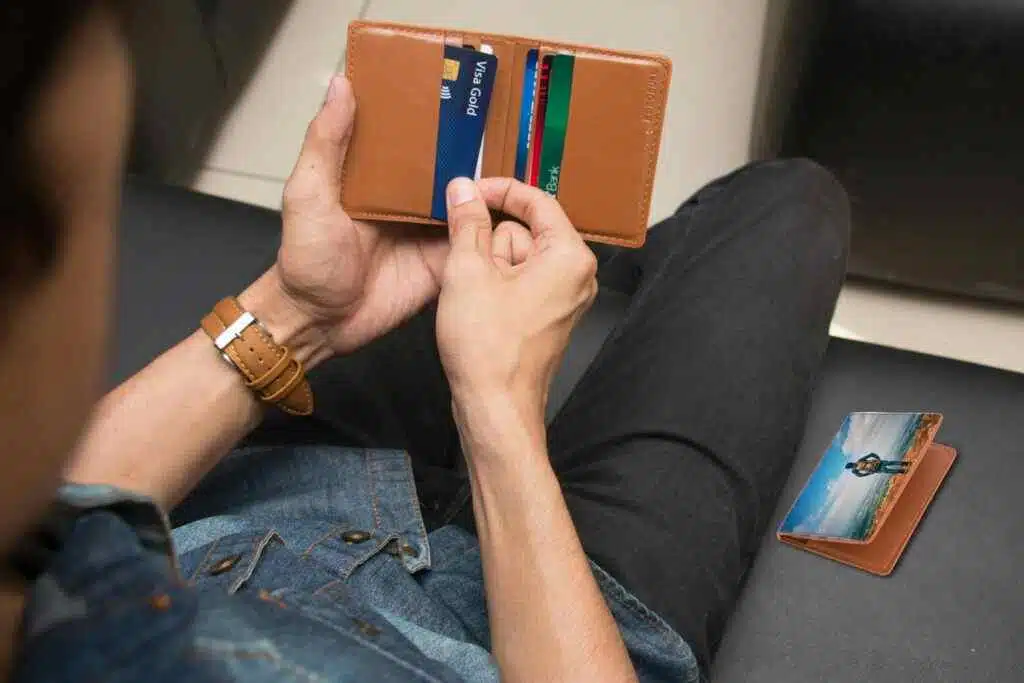 Al Barsha Emirates ID Center: Free Biometrics in 2025 15 A close-up of a man holding a wallet containing credit cards and an ID inside a room.