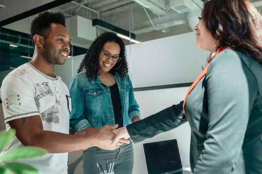 Al Ansari Balance Check: Instantly View Card Balance (2025) 26 Smiling couple shaking hands with advisor in modern office.