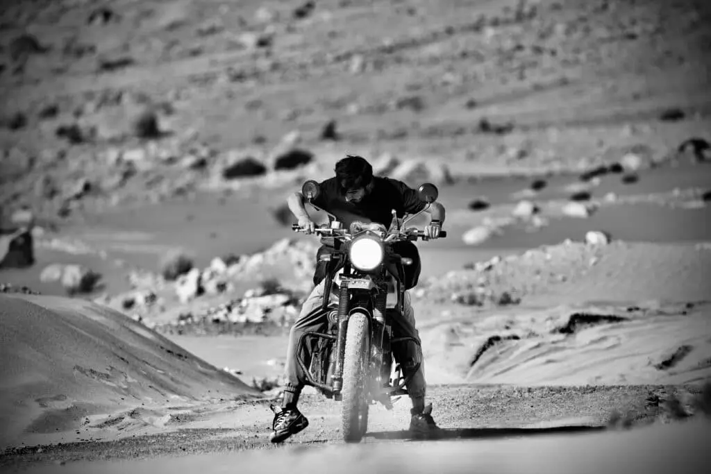 Category 2 UAE Driving License Guide 2025 | Ride Legally 5 A daring motorcyclist navigates through the challenging sandy terrain of Leh in a dynamic monochrome scene.