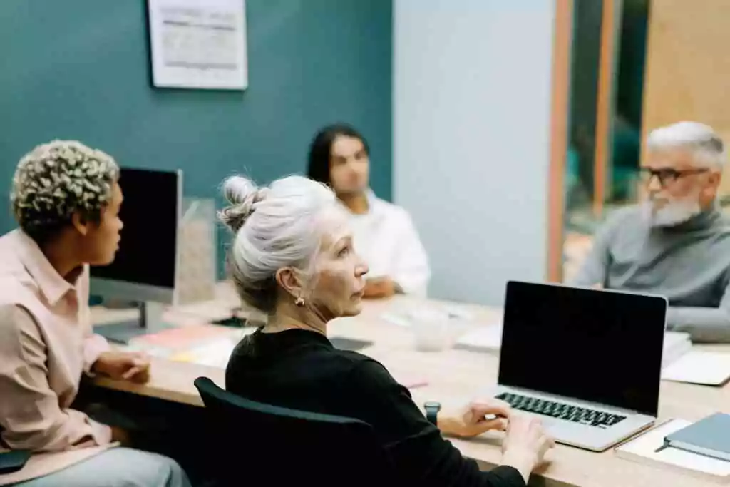 Woman in Black Sweater Sitting on Chair in Front of Macbook Pro