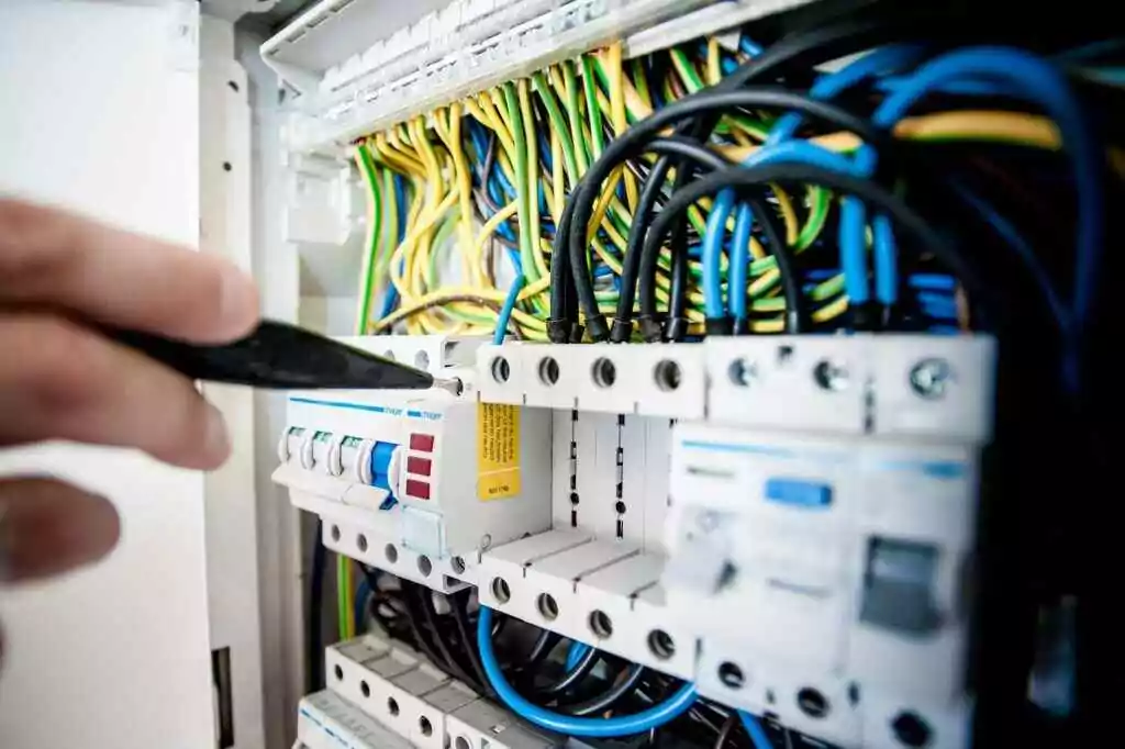 يد كهربائي يعمل على لوحة قاطع الدائرة باستخدام الأسلاك الملونة، مما يضمن توصيلات كهربائية آمنة.