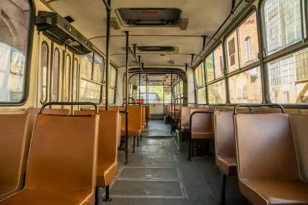 Interior view of a vintage tram showing empty brown seats under warm sunlight in Wrocław, Poland.