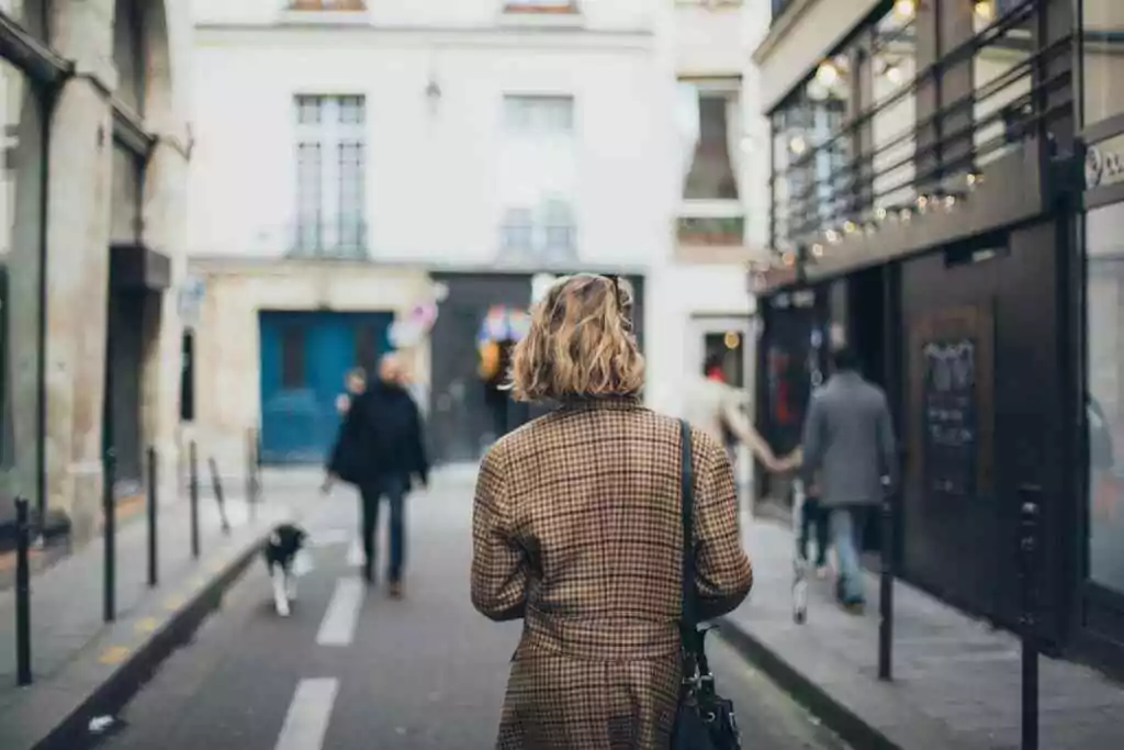 Back view of a woman walking along a quaint city street, capturing the essence of urban life.