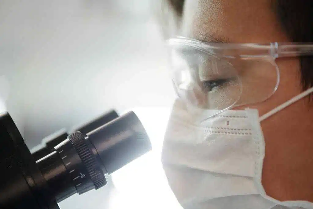 Close-up of a scientist wearing protective gear examining samples in a laboratory setting.