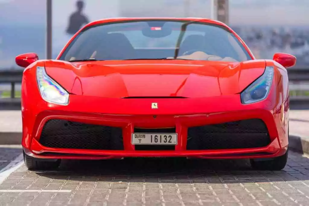 Front view of a sleek red sports car parked on a Dubai street.