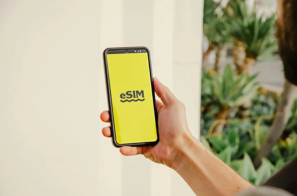 A person holds a smartphone with an eSIM logo outdoors, showcasing technology in Los Angeles.