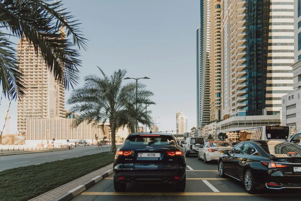 Dubai road traffic with modern skyscrapers and luxury cars in urban landscape.