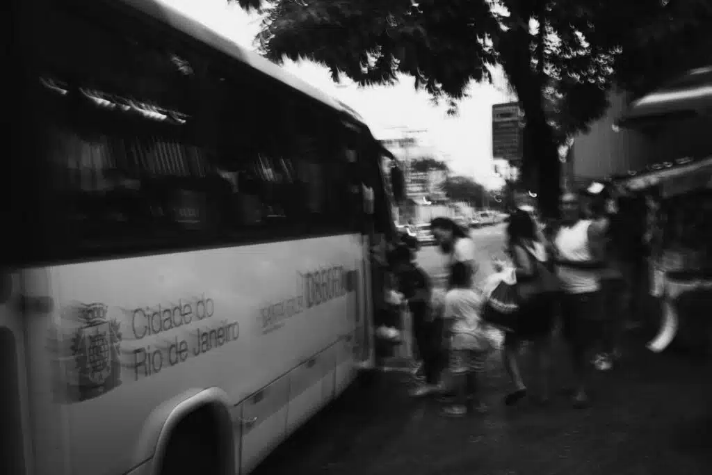Blurred black and white photo of people boarding a bus in Rio de Janeiro.