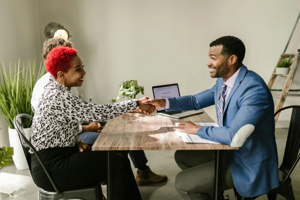 Bank professionals shaking hands indoors with smiles, capturing a successful bank account closing