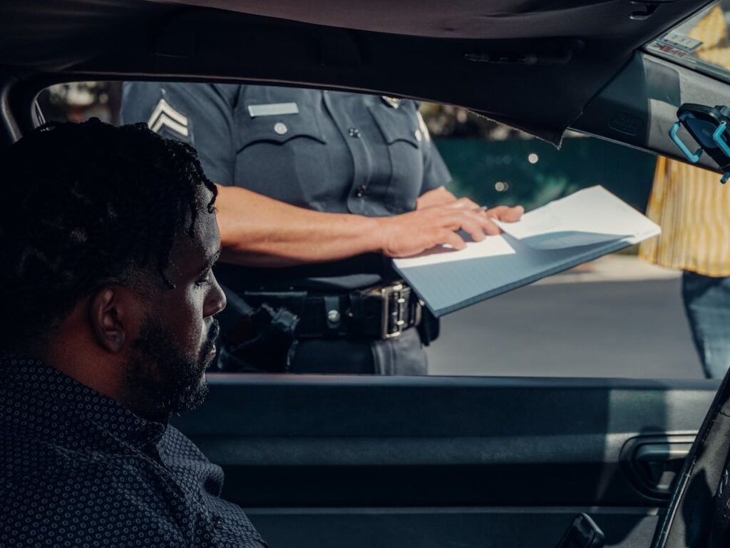 Photo of a traffic police officer standing outside a car while a man inside a car