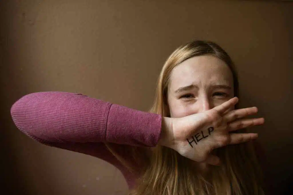 A woman having her hand on her mouth with help written on it