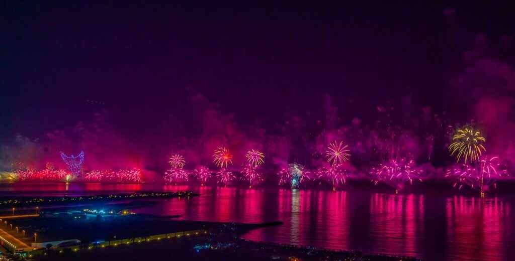الألعاب النارية المذهلة تضيء سماء الليل فوق الماء في رأس الخيمة، الإمارات العربية المتحدة.