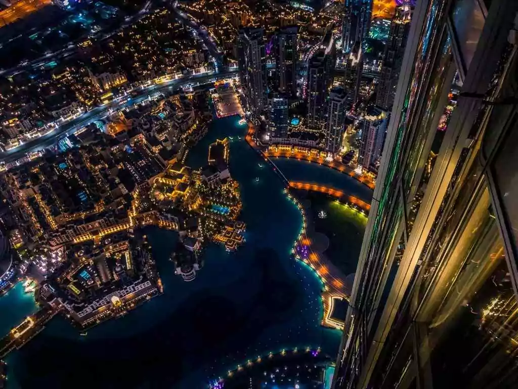 منظر جوي نابض بالحياة لمدينة دبي ليلاً مع ناطحات السحاب المضيئة والمناظر الطبيعية الحضرية.