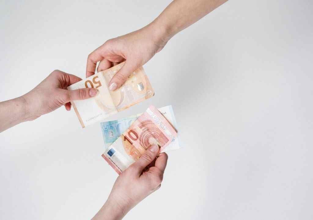 لقطة مقربة لأيدي تتبادل أوراق اليورو، والتي ترمز إلى التمويل والمعاملات.