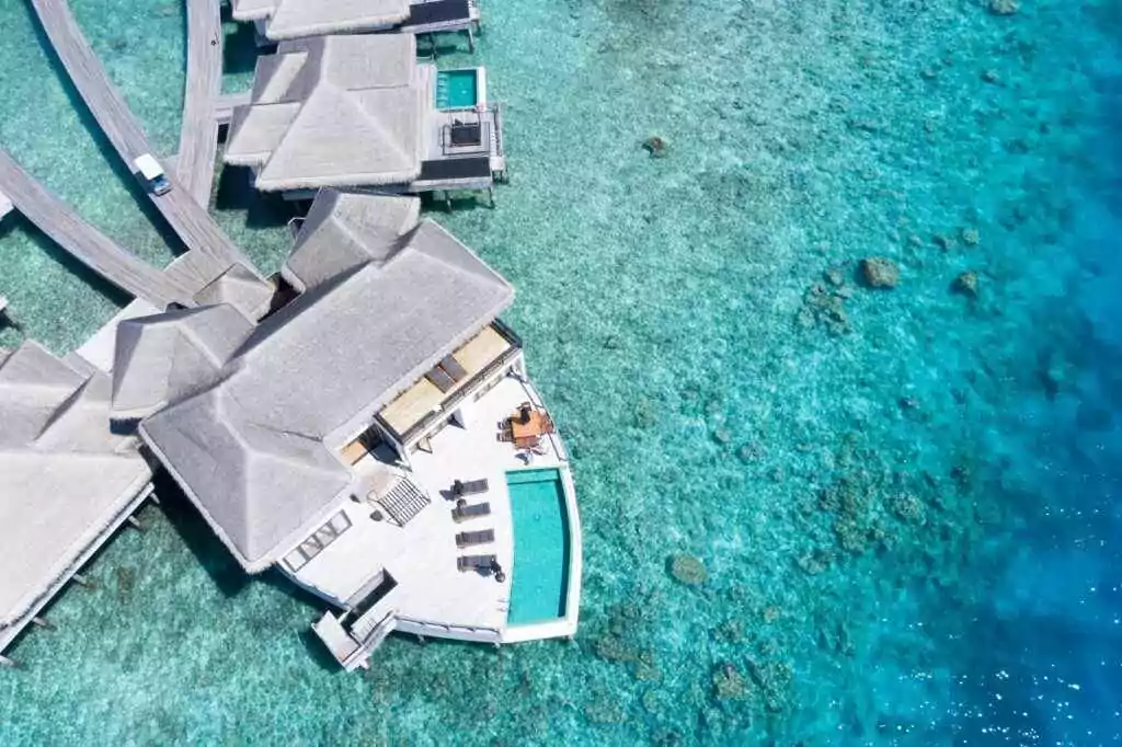 Discover a breathtaking aerial view of a luxury resort over vibrant blue waters in the Maldives, perfect for relaxation and escape.
