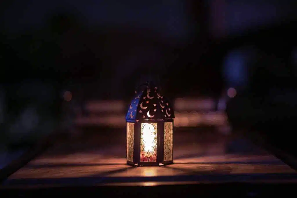 A beautifully decorated lantern illuminates a dark room, symbolizing Ramadan.