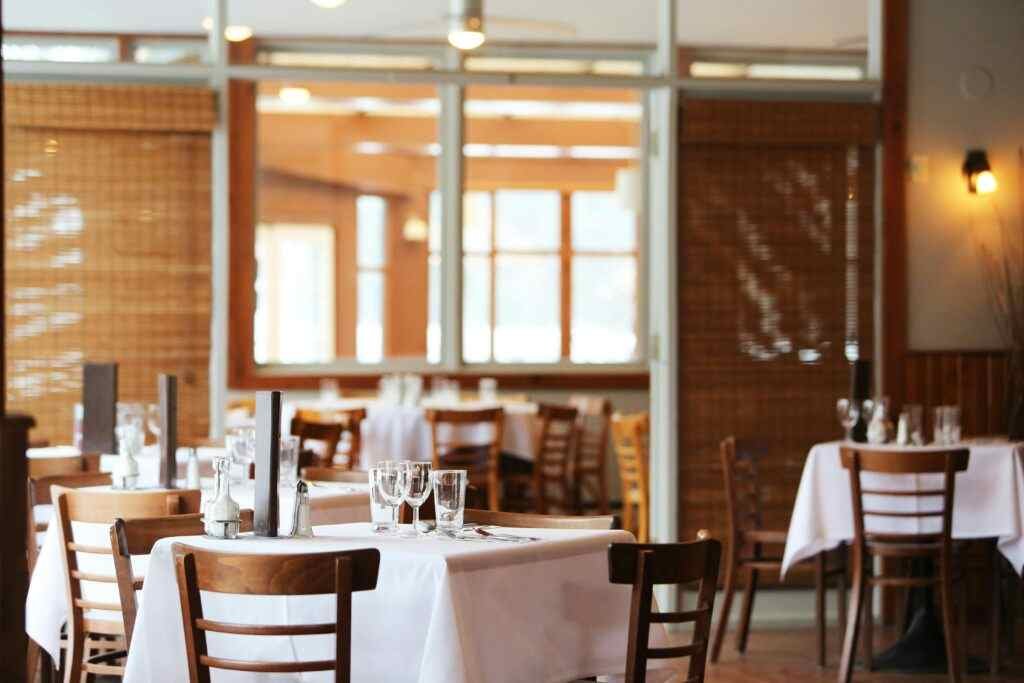 Where to Eat Cheap in Abu Dhabi? 5 Best Affordable Spots! 12 A serene restaurant interior with wooden chairs and tables set with glasses, ready for dining.