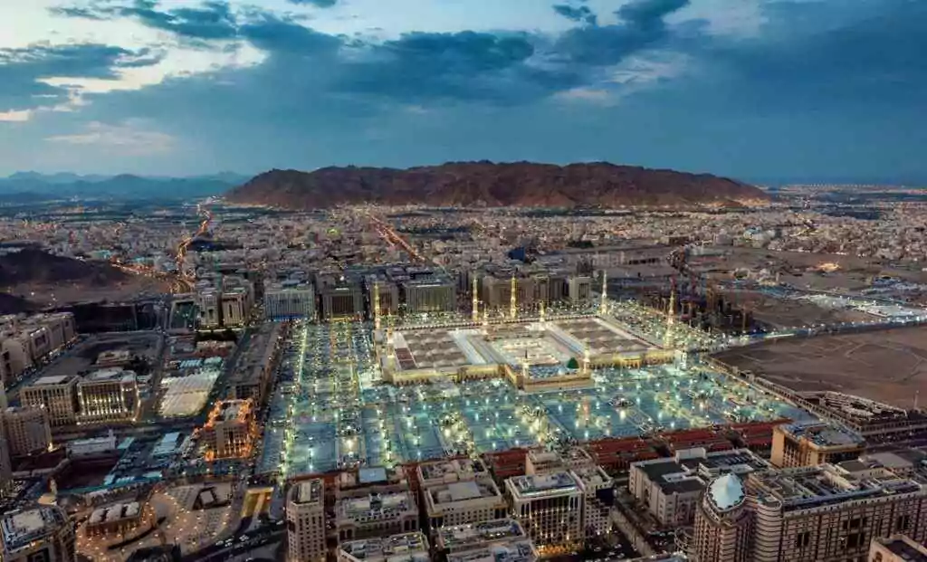 منظر جوي مذهل للمسجد النبوي الشريف في المدينة المنورة عند الغسق، يظهر عظمة المسجد النبوي المضيء.