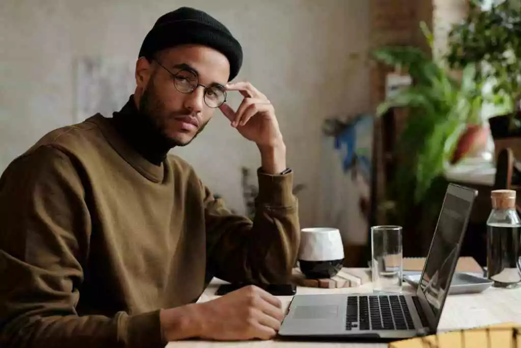 Stylish man working on a laptop from an indoor workspace with plants.
