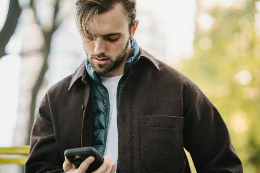 Young man gazing at smartphone in an urban outdoor setting.