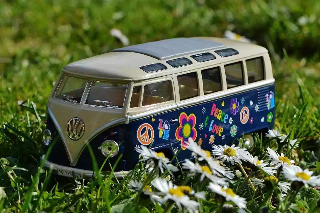 Close-up of a classic Volkswagen toy car decorated with peace signs in a grassy field.