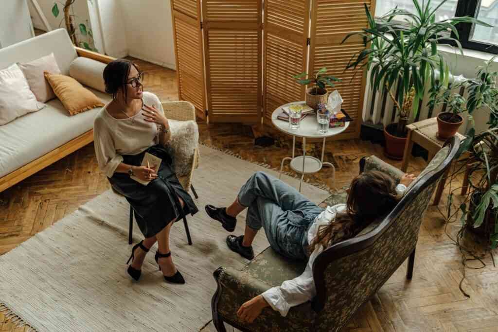 What Is Lifestyle Coaching (And Why It’s Different Here) Two women engaged in a lifestyle consultancy session in a warm, inviting interior with plants and natural lighting.