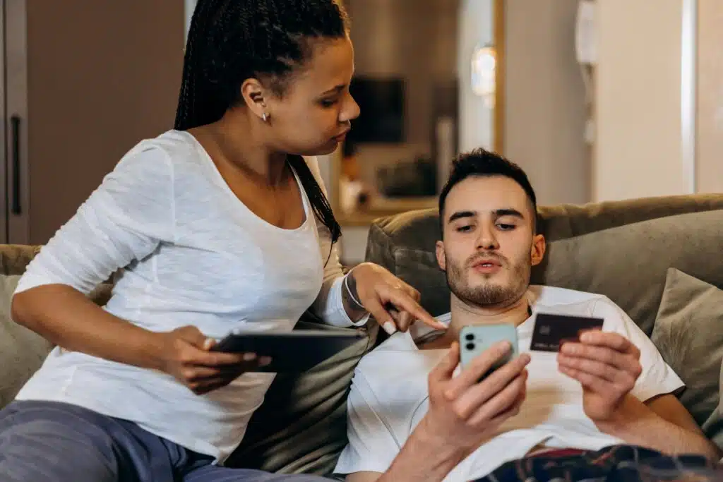A couple comfortably doing sim renewal at home using a smartphone and tablet.