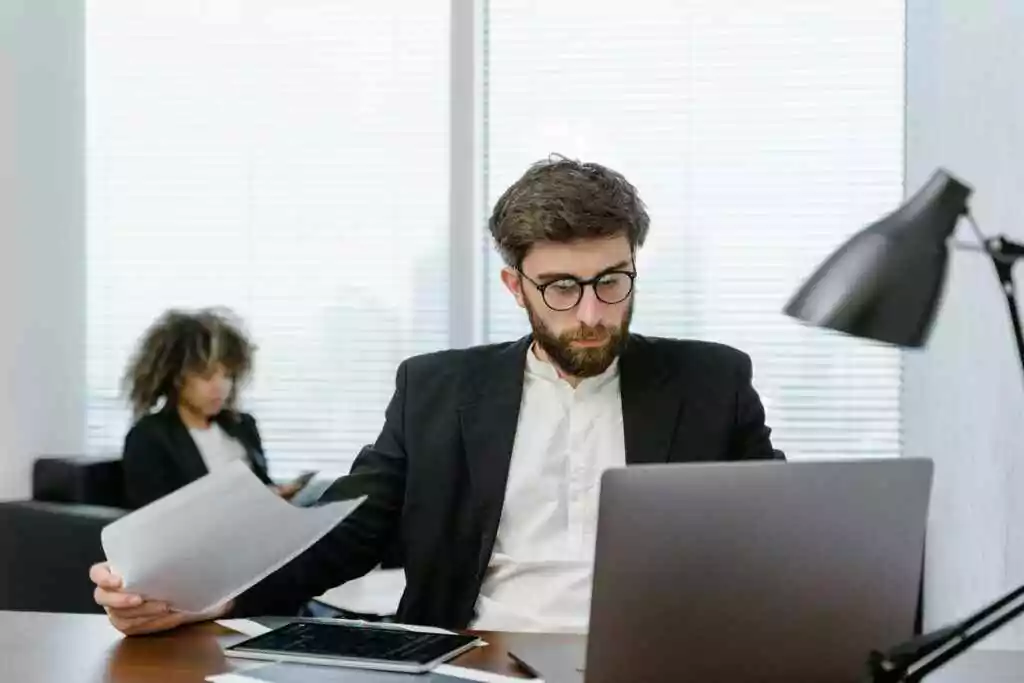 Two business professionals analyzing data on a laptop in a modern office setting, focusing on strategy.