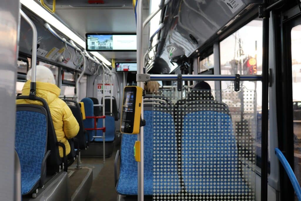Passengers sitting inside a public bus with visible interior and ticket machine.