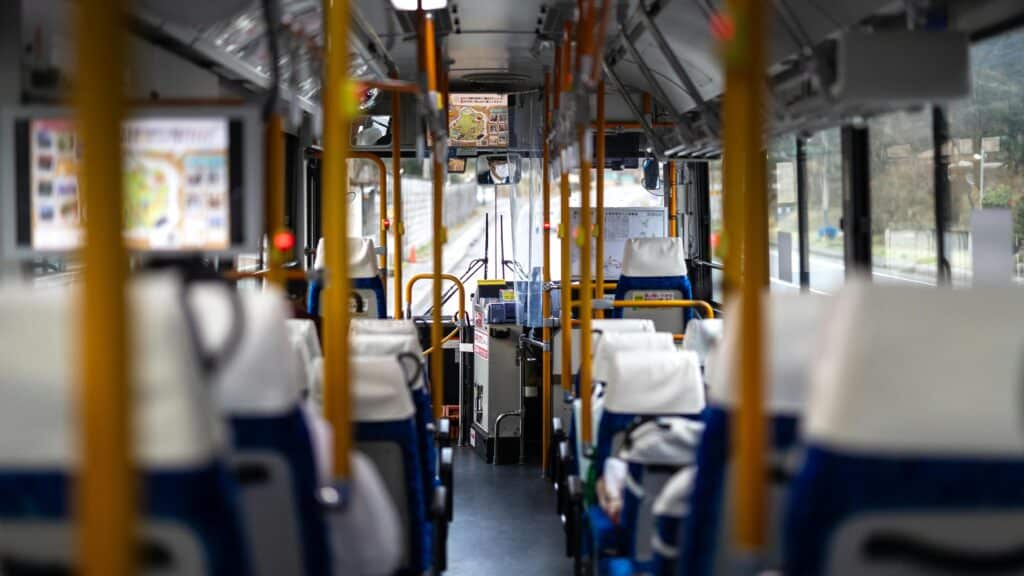 Interior view of a modern Japanese bus with empty white seats and vibrant colors.
