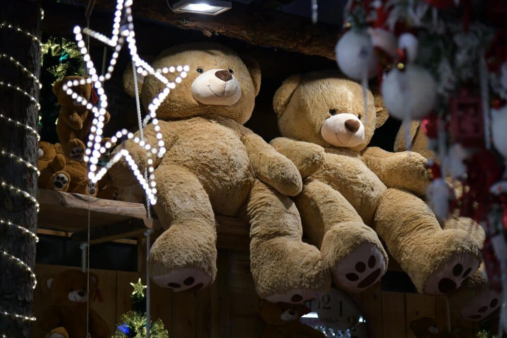 Giant teddy bears surrounded by festive lights in a charming indoor setting.
