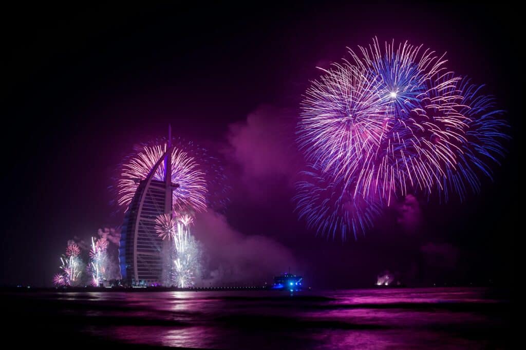 Fireworks illuminate Dubai's Burj Al Arab during a vibrant night celebration.