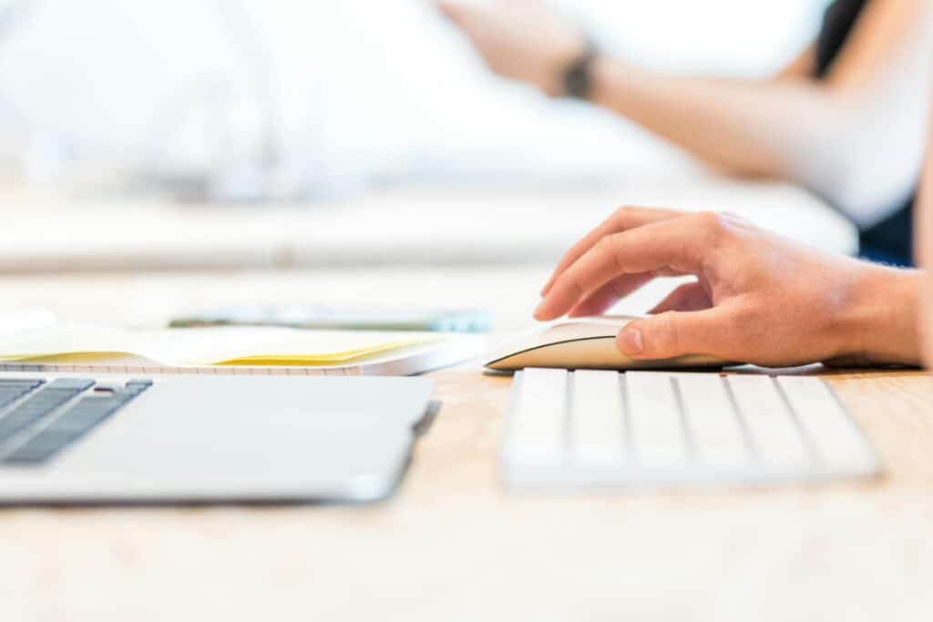 CPS Tester Online – Test & Boost Your Click Speed (1–60s) A person working at a laptop with a wireless mouse and keyboard in a bright office setting.