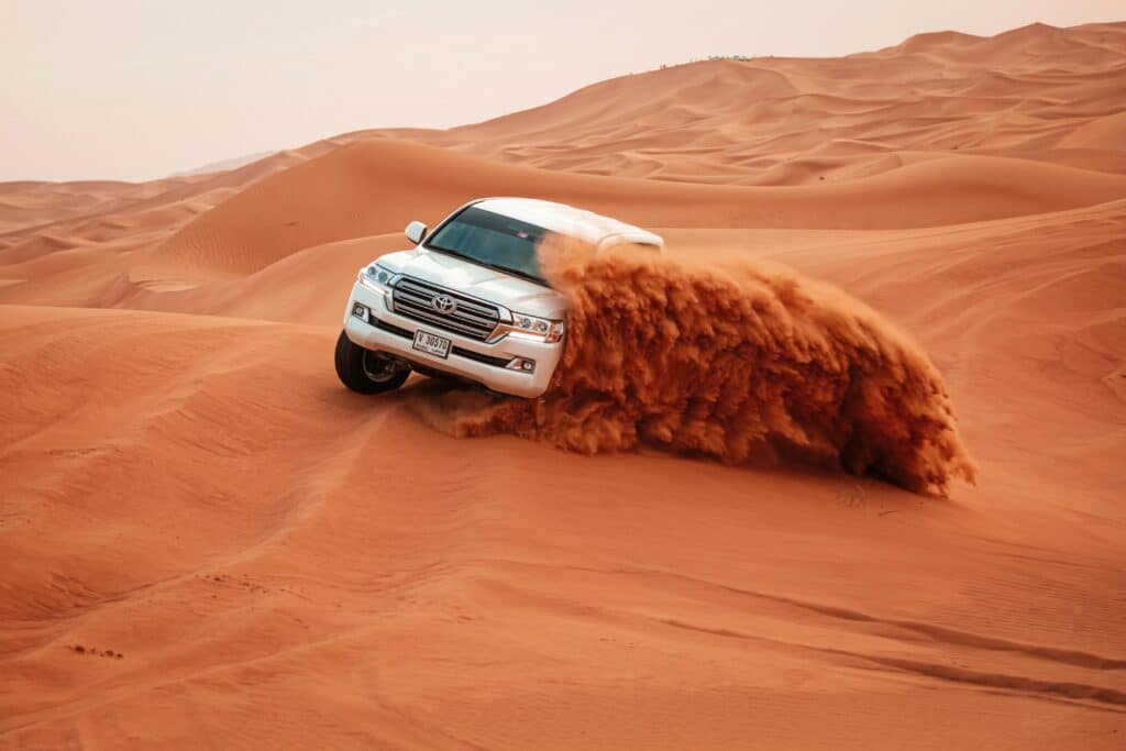 Secure Your Dubai Number Plate Now — All Scenarios 11 A Toyota Land Cruiser drives through the vast sandy dunes on an exciting off-road adventure.