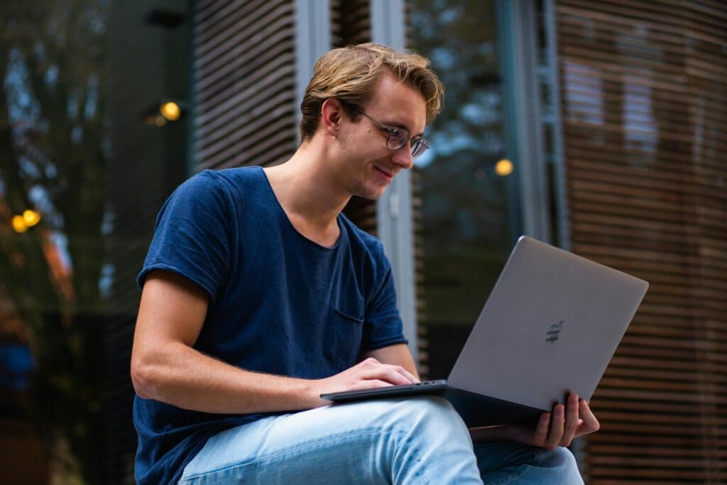 UAE GPA Calculator – Convert 4.0 & 5.0 Scale Instantly A young man sitting outdoors in Leiden, Netherlands, working on a laptop.