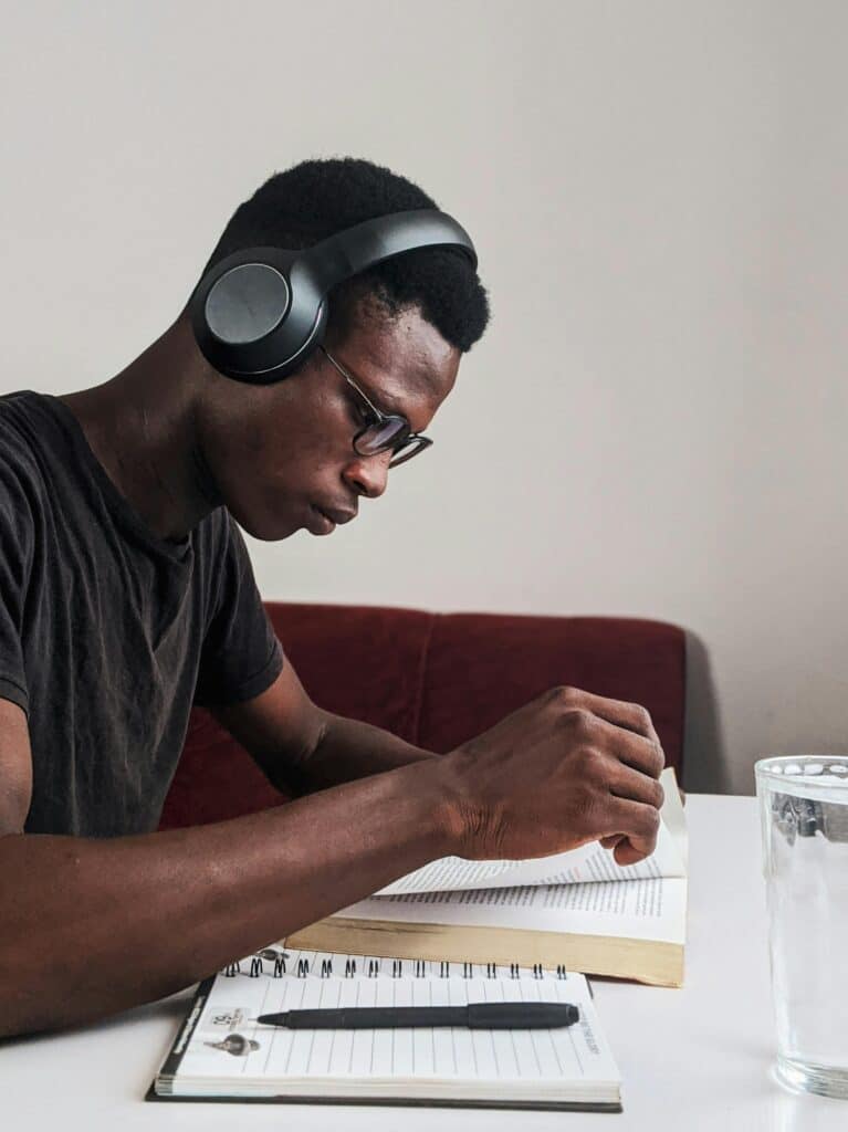 UAE GPA vs. International GPA An adult man intensely studying with headphones, pen, and notebook at a desk indoors.