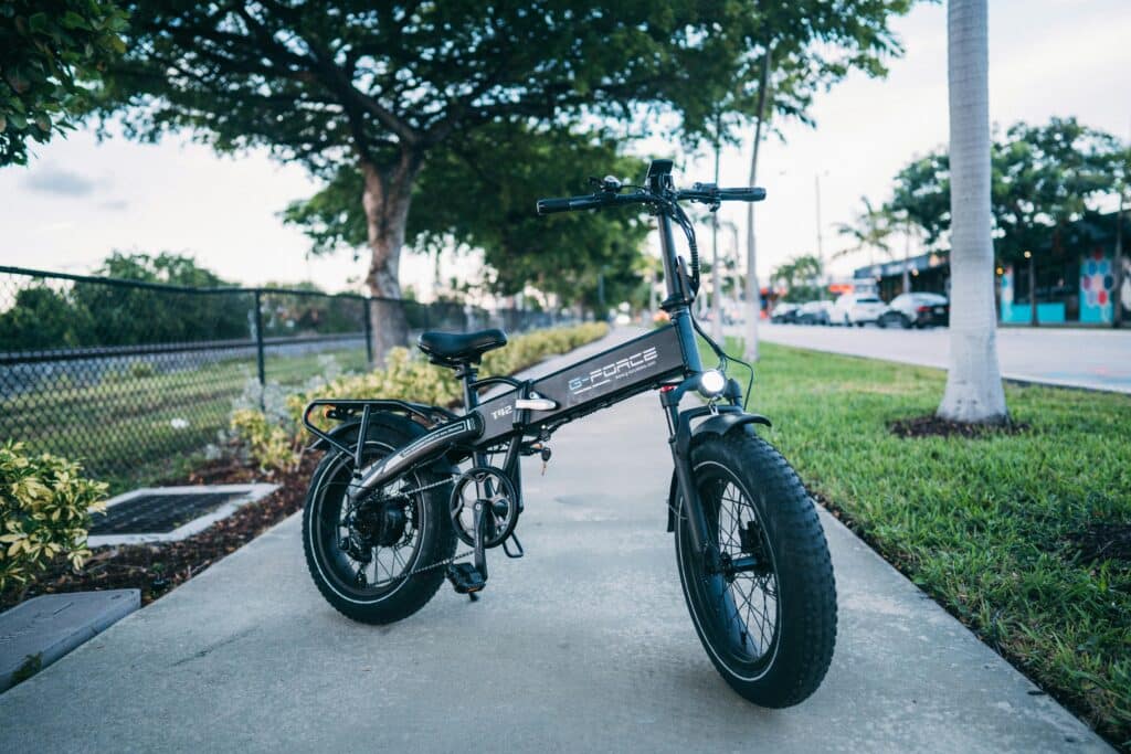 Sleek electric bike parked on a city sidewalk surrounded by greenery.